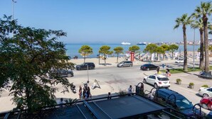 A coastal street with parked cars, palm trees, and a clear view of the sea. - Adore Boutique Hotel (Vlorë)
