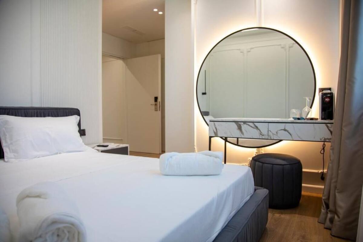 A hotel room with a bed, a round mirror, a small table, and a nightstand.