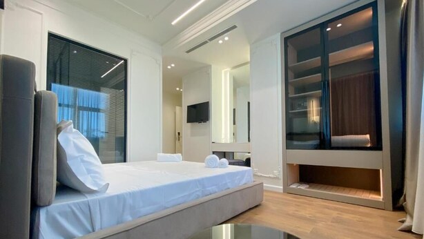 A modern bedroom with a bed, a sofa, a TV, and a wardrobe. - Adore Boutique Hotel (Vlorë)