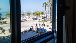A view from a window overlooking a parking area with palm trees and a body of water. - Adore Boutique Hotel (Vlorë)