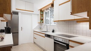A modern kitchen with white cabinets, a stainless steel refrigerator, a built-in oven, and a window above the sink. - Athens Golden Light Premium Residence (Athens)