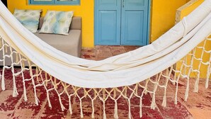 A hammock in a room with a yellow wall, a blue door, and a window with curtains. - CASA ENCANTADA  (Santa Marta)