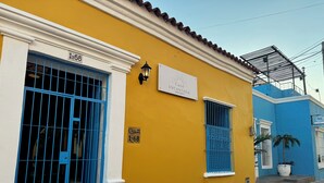 A yellow building with a blue gate, a sign reading "Casa Encantada Santa Marta," and a small balcony with a potted plant. - CASA ENCANTADA  (Santa Marta)