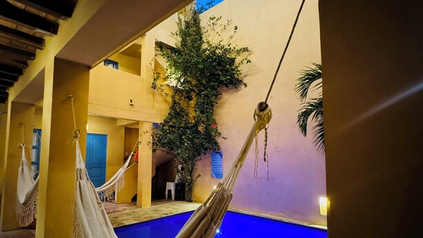 A hammock by a pool with a view of a building and a tree. - CASA ENCANTADA  (Santa Marta)