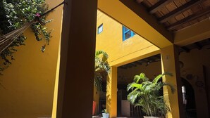 A covered courtyard with yellow walls, a tiled floor, and potted plants. - CASA ENCANTADA  (Santa Marta)
