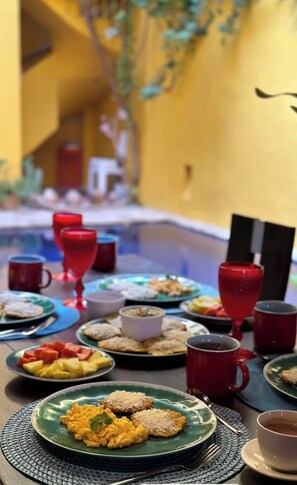 A table set with various dishes, including scrambled eggs, toast, and fruit, along with red and white cups, likely containing beverages. - CASA ENCANTADA  (Santa Marta)