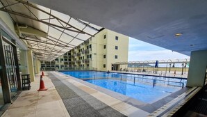 Ein überdachter Innenpool mit gefliestem Gang und einem Gebäude im Hintergrund.