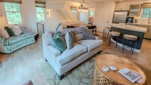 En moderne stue med sofa, spisebord og et køkkenområde med bar.