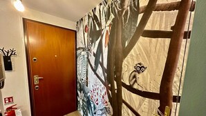 Un corridoio con una porta in legno, un estintore e un murale raffigurante una scimmia.
