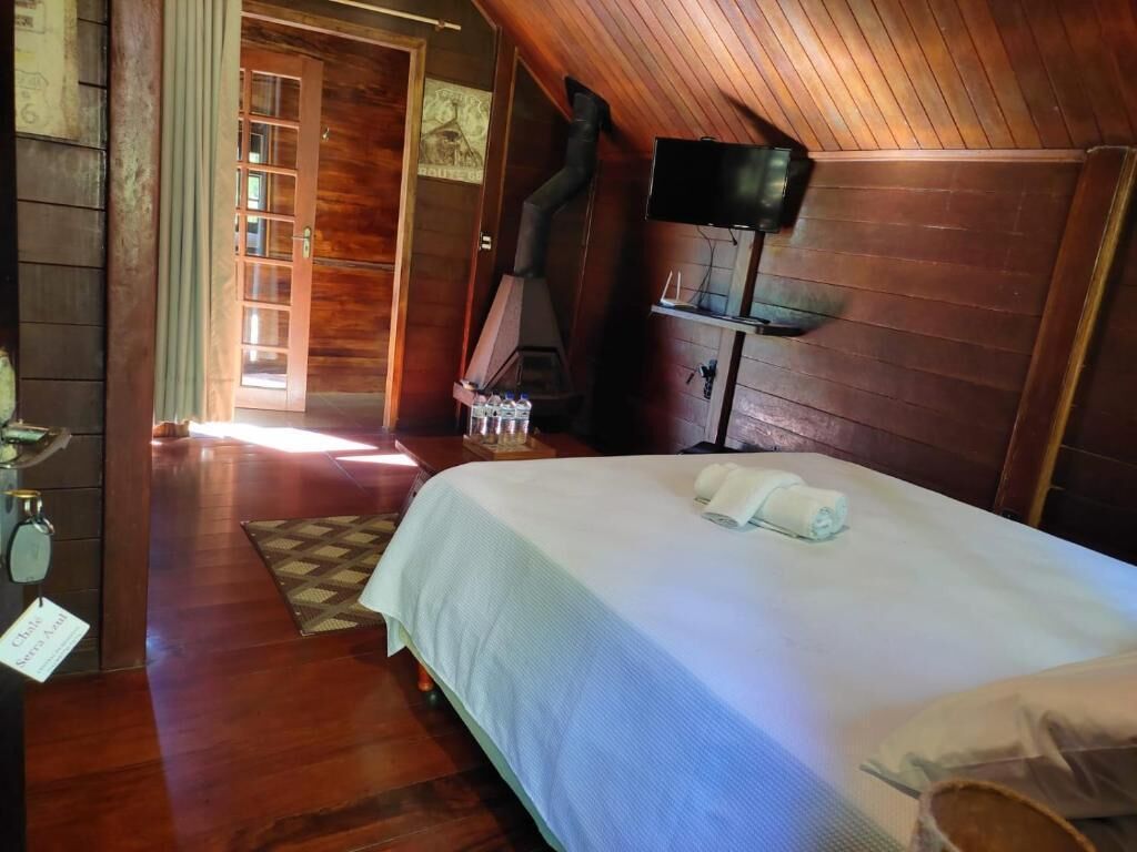 Una habitación de madera con una cama, un televisor y una chimenea.