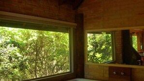 Une pièce dotée de grandes fenêtres, d’un mur en briques et d’un miroir qui reflète l’intérieur.