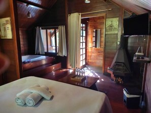 Relax in a warm, inviting room with a large bed, fireplace, and mounted TV.