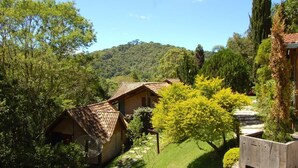 Un paysage rural avec des maisons traditionnelles en bois, entouré d’une végétation luxuriante et dominé par une colline en arrière-plan.