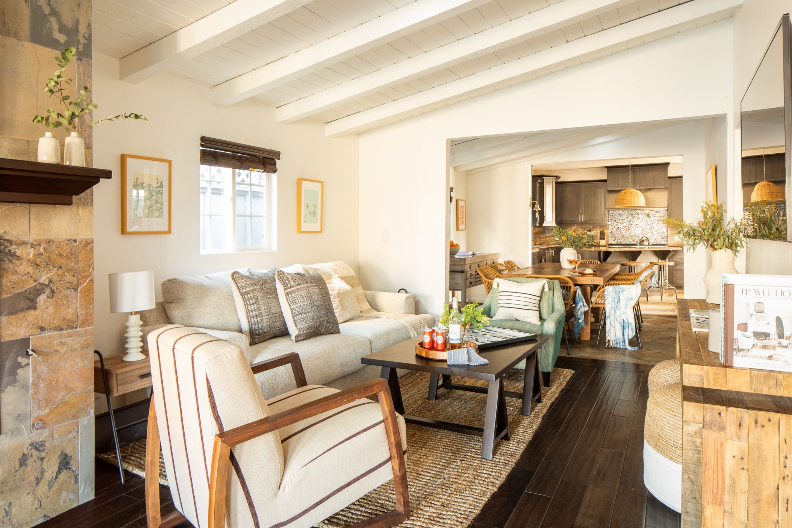 A spacious living room with a sofa, armchairs, and a coffee table. A kitchen is visible in the background.