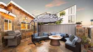 A patio with a grill, seating, and a fire pit. - Sand Castle by Avantstay Beach House on Balboa Peninsula w Patio Hot Tub (Newport Beach)