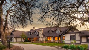 A large, multi-story house with a stone chimney, multiple windows, and a driveway leading to the entrance. - Cathedral by Avantstay Charming Secluded Estate w Sauna Pool Table Views of the Rolling Hills (Templeton)