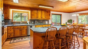 A spacious kitchen with wooden cabinets, a large island, and a dining area with wooden chairs.