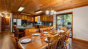 A spacious kitchen with wooden cabinets, a central island, and a dining area with wooden chairs and a table set for four.