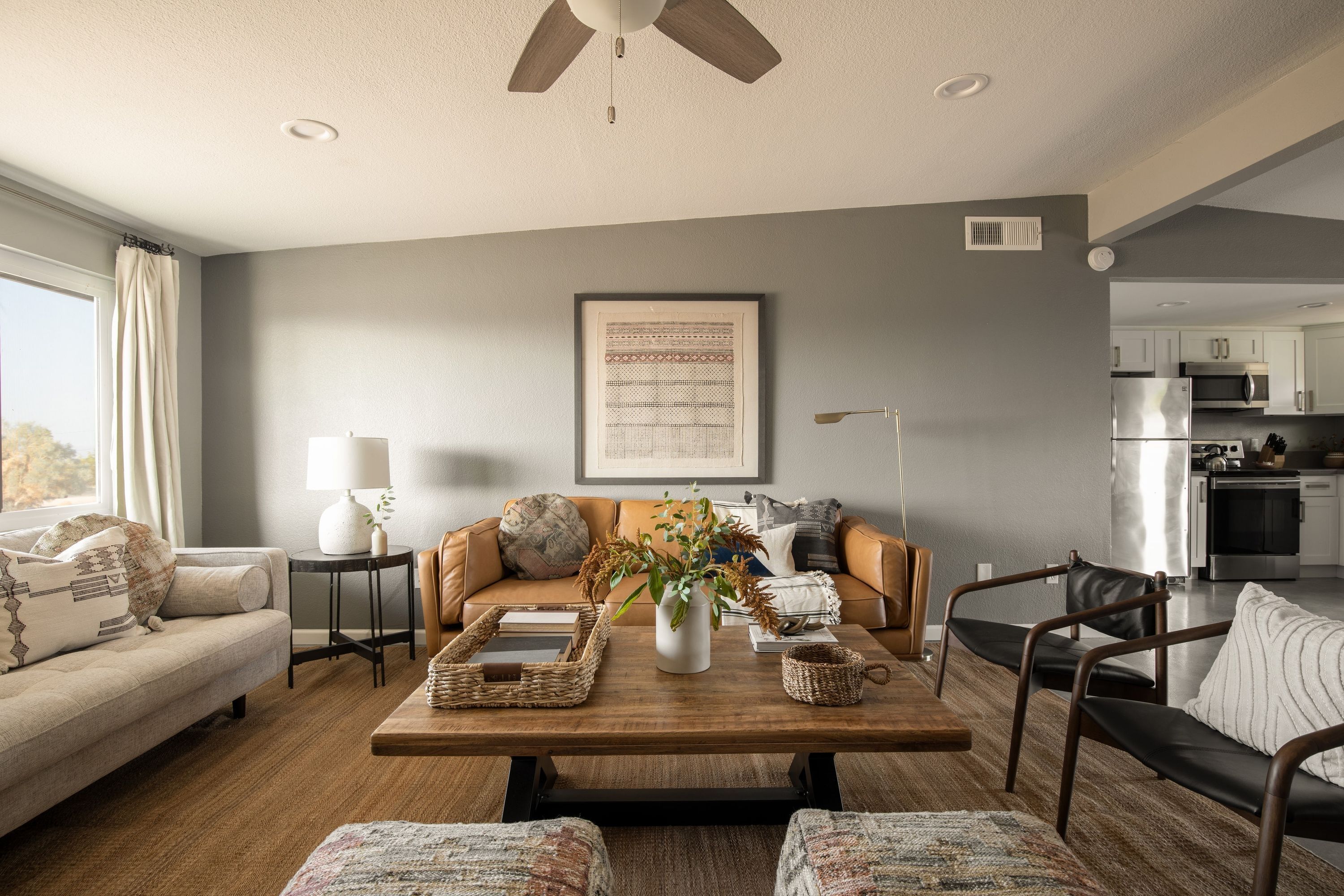 A modern living room with a sofa, coffee table, and a view into the kitchen.