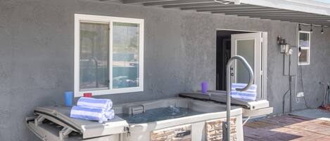 An outdoor hot tub with a stone facade, a window, and a patio area.