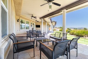 Une terrasse extérieure aménagée avec des meubles en osier, des ventilateurs de plafond et une vue sur le paysage.