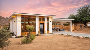 A modern house with a large front porch, a wooden deck, and a desert landscape. - Chicory by Avantstay Modern Desert Retreat w Hot Tub (Joshua Tree)