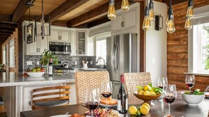 A modern kitchen with wooden beams, stainless steel appliances, and hanging light fixtures.