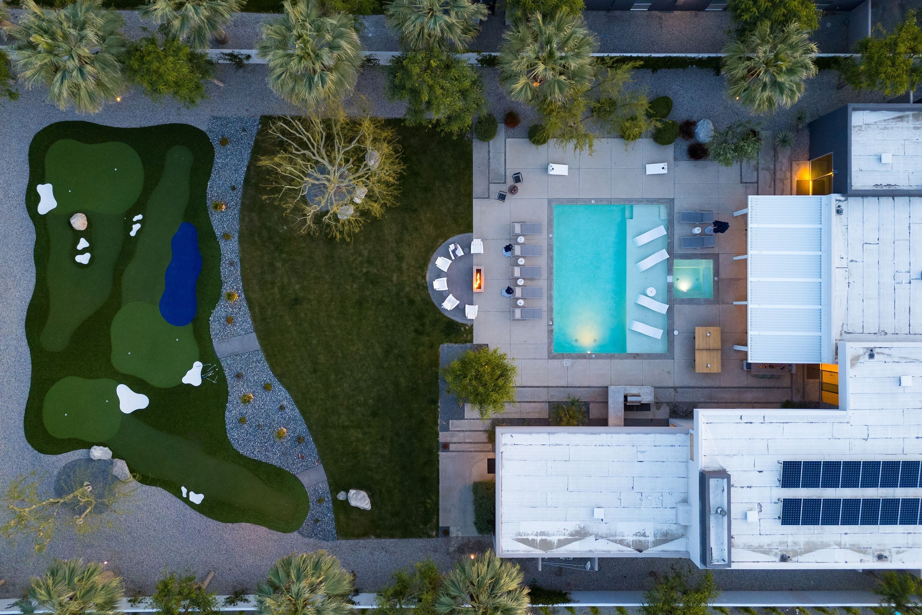 An aerial view of a property with a swimming pool, outdoor seating area, and a golf course.