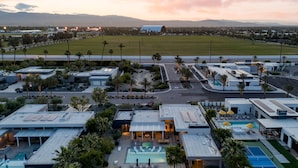 Un hotel moderno con piscina sul tetto, area salotto esterna e vista su un campo sportivo.