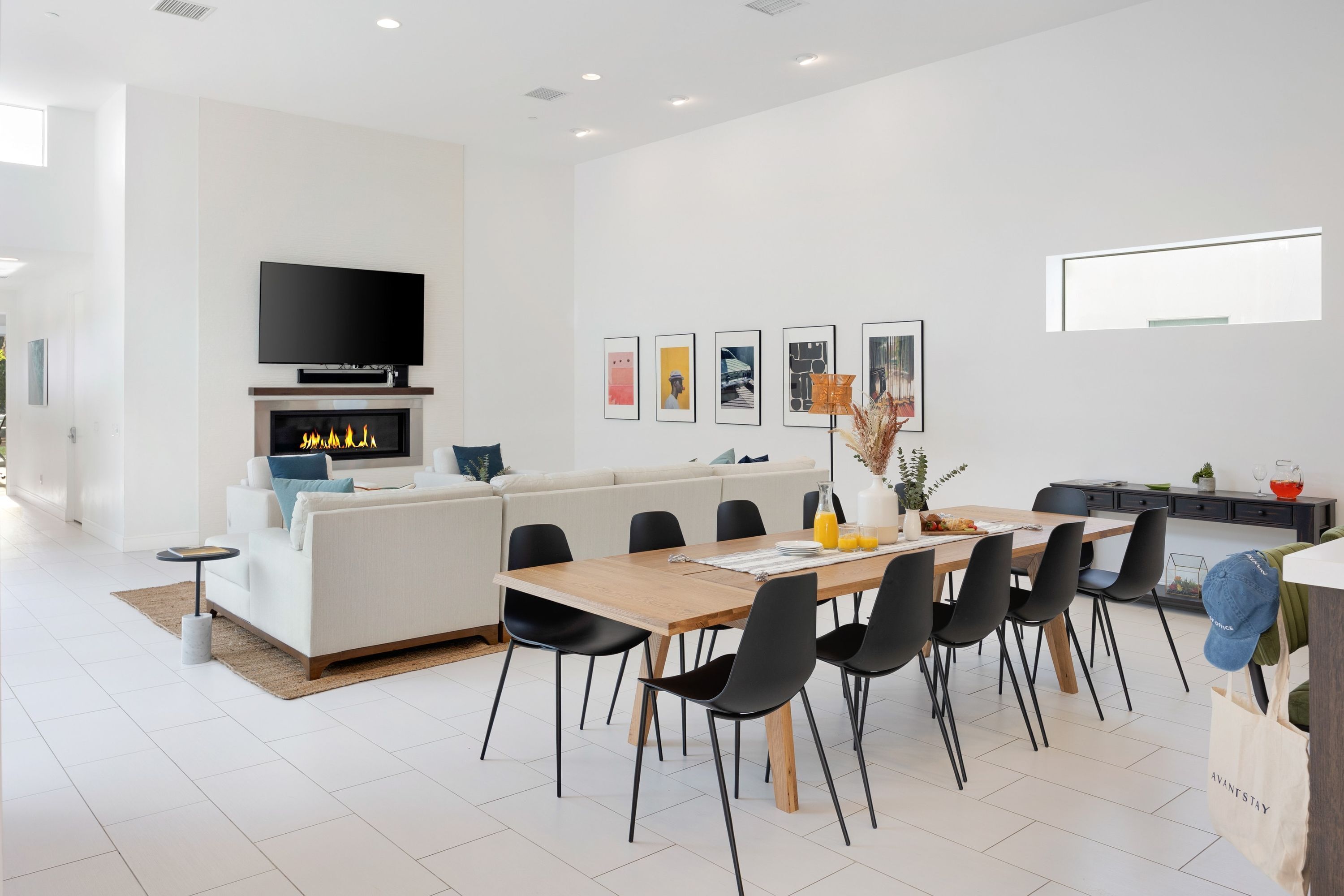 A modern living room with a sofa, a TV, a fireplace, and a dining area with a table and chairs.