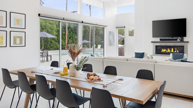 A modern living room with a dining area, large windows, a fireplace, and a TV. - Polo Villa 7 by Avantstay Features Entertainer s Backyard Game Room 260316 5 Bedrooms (La Quinta)