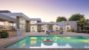 A modern house with a swimming pool, outdoor seating, and a covered patio area. - Polo Villa 7 by Avantstay Features Entertainer s Backyard Game Room 260316 5 Bedrooms (La Quinta)