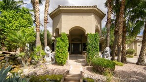 A building with a central entrance, flanked by statues and palm trees, leading to a stone pathway. - Arcadia by Avantstay Breathtaking Oasis in Scottsdale w Pool Hot Tub Game Room (Scottsdale)