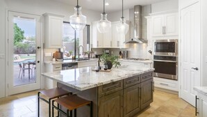 A modern kitchen with white cabinetry, a large island with a marble countertop, stainless steel appliances, and pendant lighting. - Arcadia by Avantstay Breathtaking Oasis in Scottsdale w Pool Hot Tub Game Room (Scottsdale)