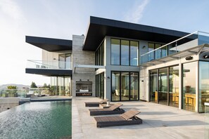 A modern house with a swimming pool, lounge chairs, and a glass-enclosed patio. - Belleza by Avantstay Hilltop Mansion w Pool Panoramic Views Ultra Modern Interior (Glen Ellen)