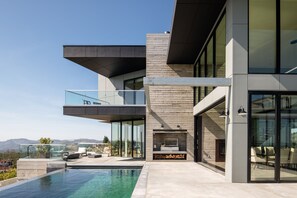 A modern house with a swimming pool, outdoor seating, and a large glass window. - Belleza by Avantstay Hilltop Mansion w Pool Panoramic Views Ultra Modern Interior (Glen Ellen)