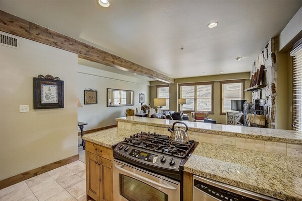 A kitchen with granite countertops, a gas stove, and wooden cabinets.
