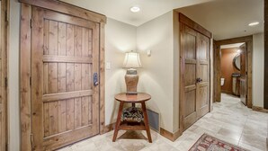 A hallway with wooden doors, a lamp, and a rug.