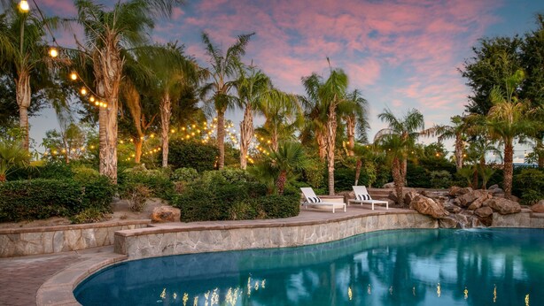A swimming pool with lounge chairs, surrounded by palm trees and a stone pathway. - Villa Verbena by Avantstay Expansive Estate w B-ball Court Pool Spa Entertainer s Yard (Indio)
