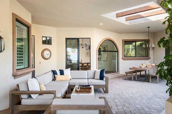 A sunlit patio with a sofa, a table, and a dining set. - Villa Verbena by Avantstay Expansive Estate w B-ball Court Pool Spa Entertainer s Yard (Indio)