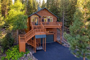Une cabane dotée d’une terrasse, d’un garage et d’un escalier menant à l’entrée.