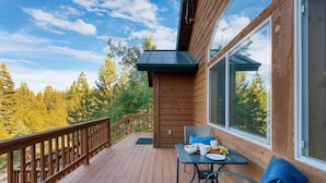 A wooden deck with a table and chairs, overlooking a forest. - Golden Summit by Avantstay Stunning Secluded Cabin w Access to Tahoe Donner (Truckee)