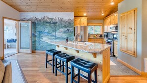 A kitchen with wooden cabinets, a granite countertop, and a painting of a mountainous landscape. - Golden Summit by Avantstay Stunning Secluded Cabin w Access to Tahoe Donner (Truckee)