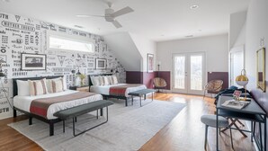A modern bedroom with a sloped ceiling, a large bed, a desk, and a chair. - Kitty by Avantstay Charming 4BR Condo in Heart of Nashville (Nashville)