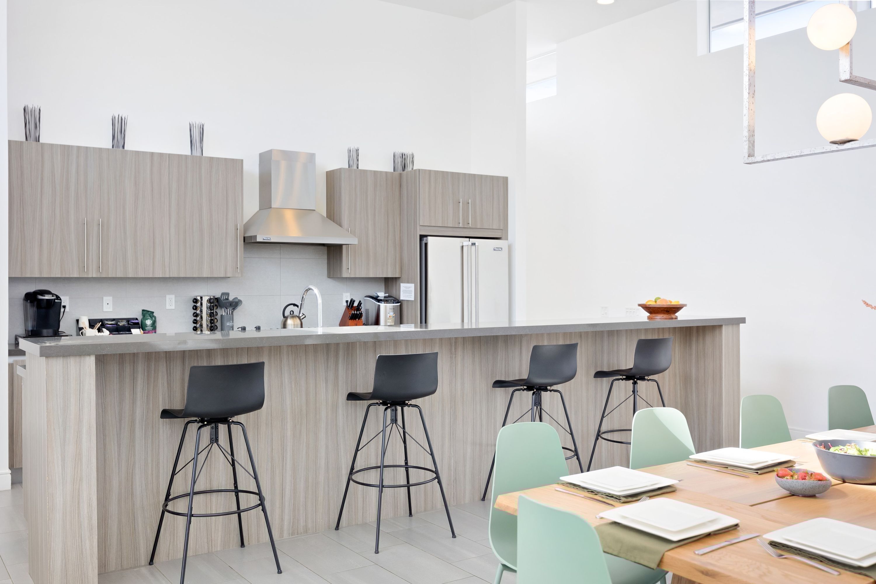 Una cocina moderna con una isla central, taburetes de bar y un comedor con mesa y sillas.