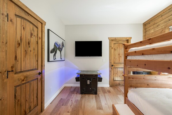 A room with a bunk bed, a flat-screen TV mounted on the wall, and a wooden cabinet.