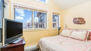 A bedroom with a bed, a television on a wooden stand, and two windows with blinds. - Blue Mesa 2 Unit Buyout by Avantstay 2 Units Centrally Located Ski In Ski Out Unit (Telluride)