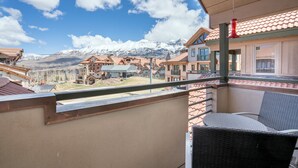 A balcony with a view of snow-capped mountains, a chair, and a building with a red roof. - Blue Mesa 2 Unit Buyout by Avantstay 2 Units Centrally Located Ski In Ski Out Unit (Telluride)