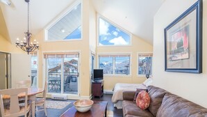 A spacious living area with a large brown leather couch, a wooden coffee table, and a dining table with chairs. There is a chandelier, a television, and a framed picture on the wall. - Blue Mesa 2 Unit Buyout by Avantstay 2 Units Centrally Located Ski In Ski Out Unit (Telluride)