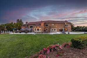 A large house with a spacious lawn, outdoor seating, and string lights.